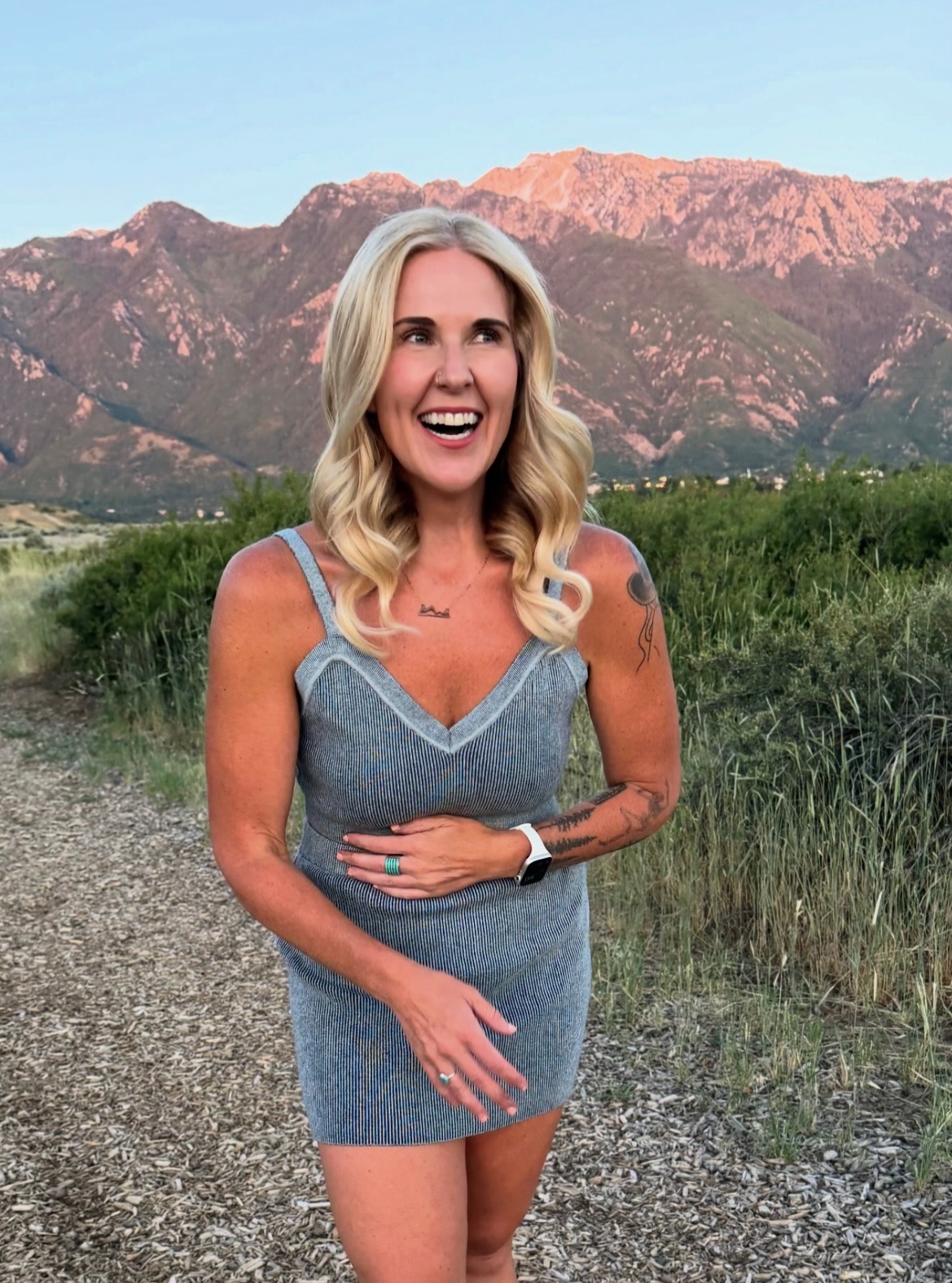 Emily, owner of Peak Beauty Salon & Spa, smiling outdoors with the Salt Lake City mountains behind her